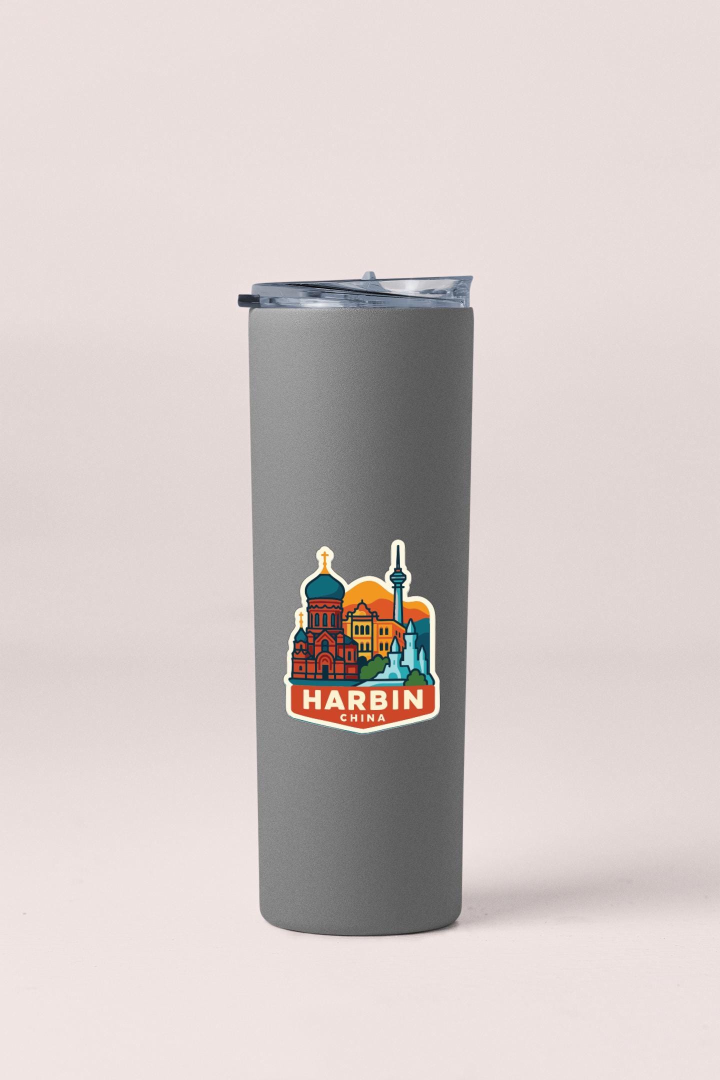 A gray insulated tumbler with a sticker depicting the Harbin City skyline.