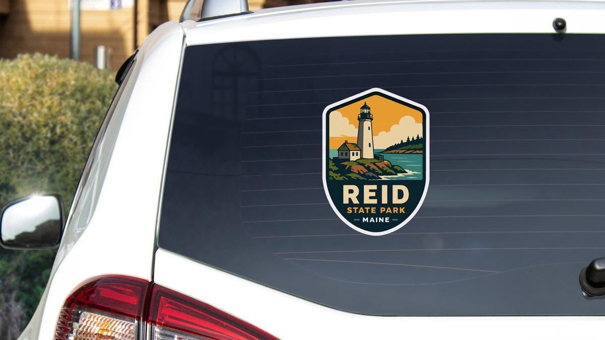A sticker on the rear window of a white car, depicting a lighthouse and the text "Reid State Park Maine".