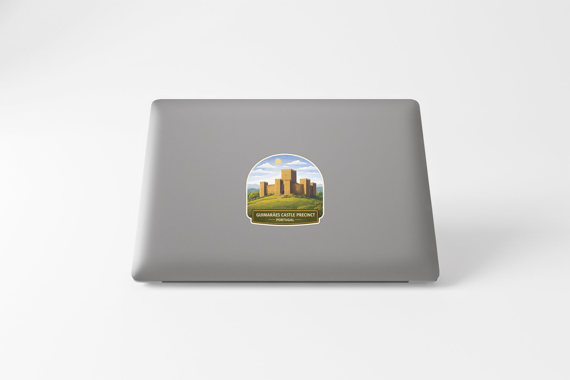 A sticker on the back of a laptop, depicting a castle or palace surrounded by a grassy field.