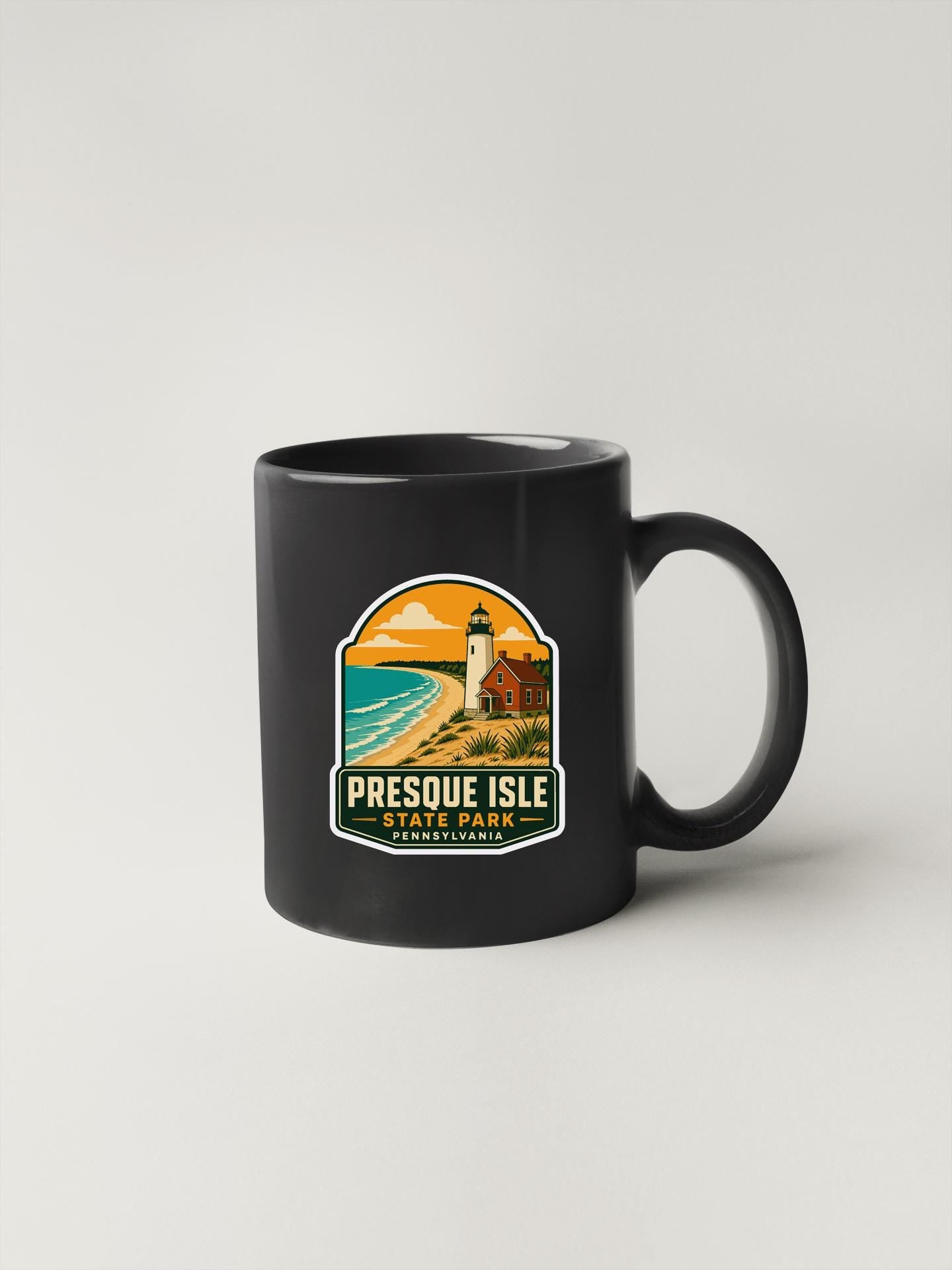 A black coffee mug with a graphic design depicting a lighthouse and a beach scene, along with the text "PRESQUE ISLE STATE PARK PENNSYLVANIA".