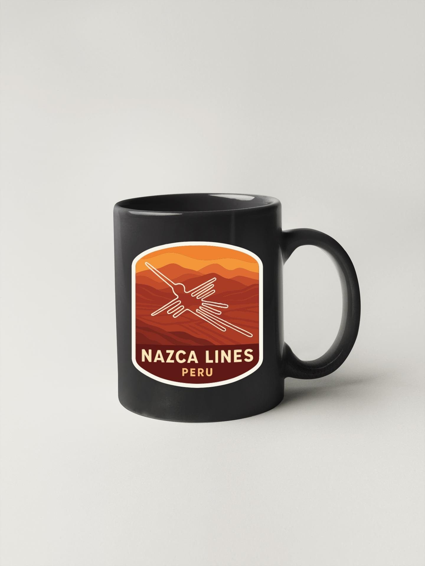 A black coffee mug with a graphic design featuring a bird and mountains, along with the text "NAZCA LINES PERU".