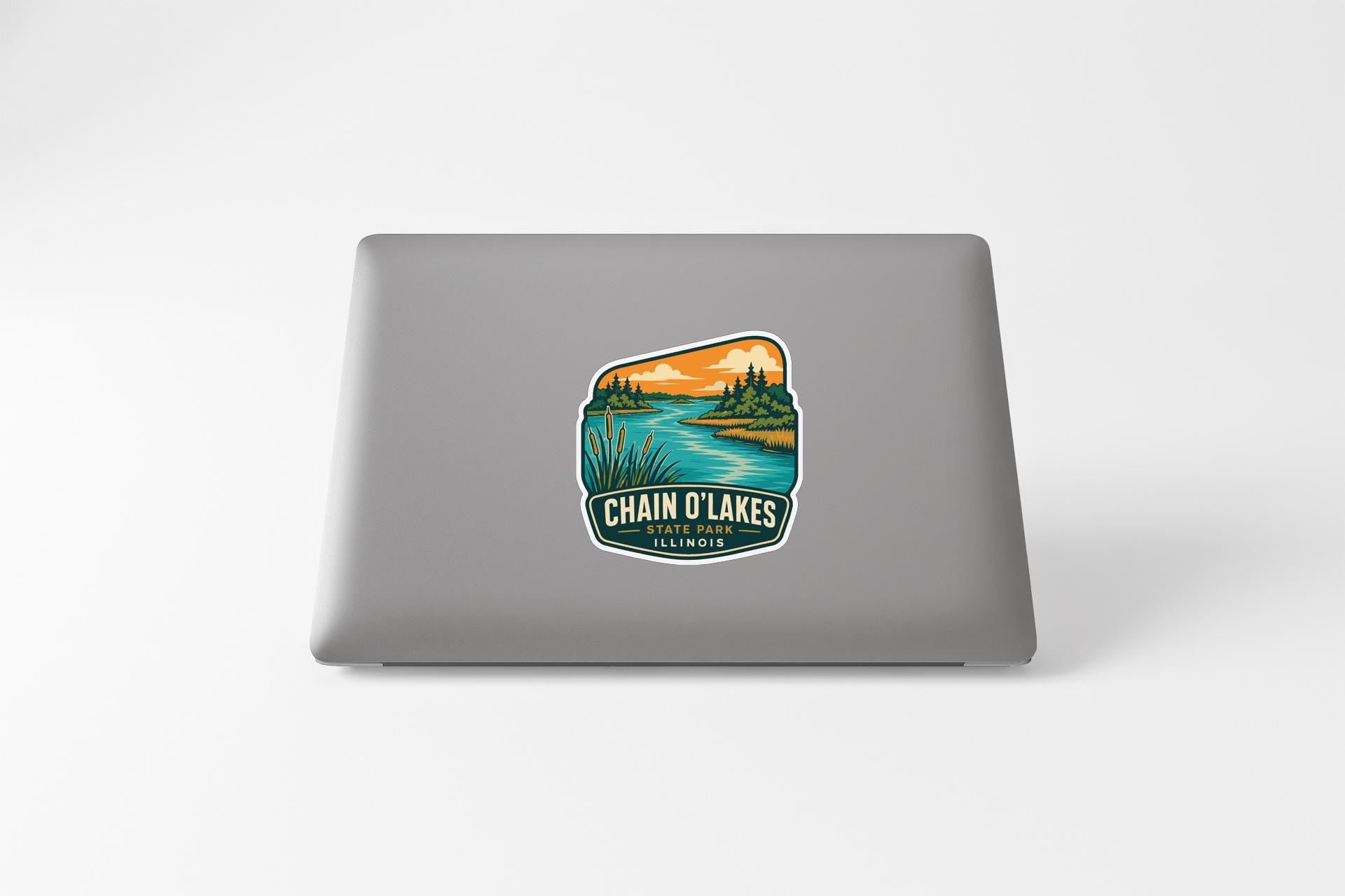 a sticker on the back of a laptop that displays a scenic landscape with a river, trees, and mountains.