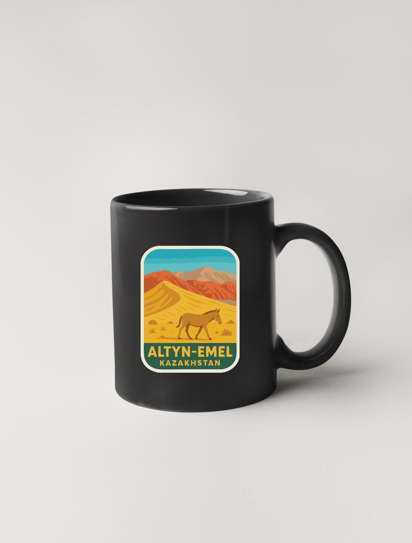 A black coffee mug with a graphic design depicting a desert landscape with mountains and a horse.