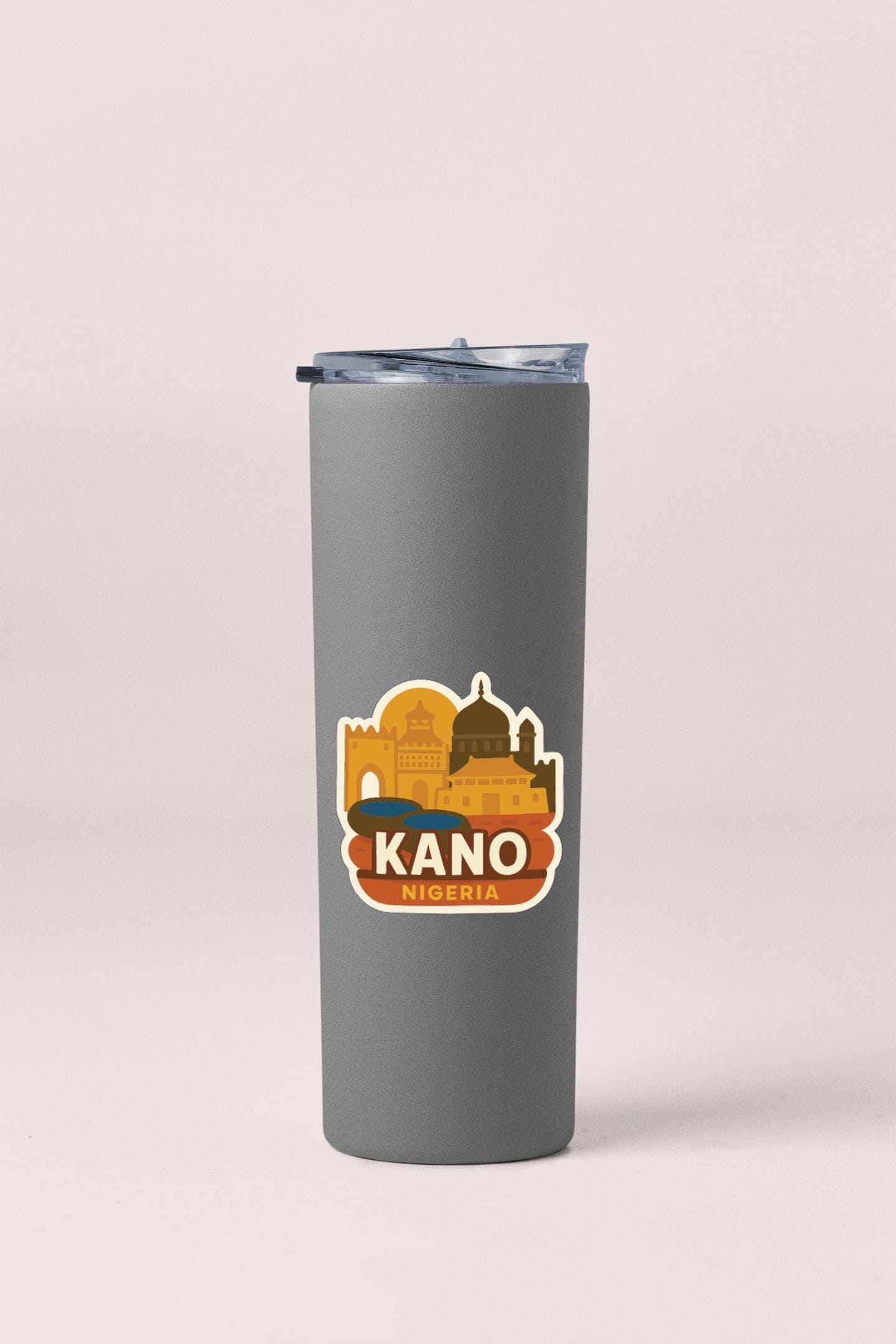 A gray insulated tumbler with a sticker featuring a city skyline and the word "KANO" printed on it.
