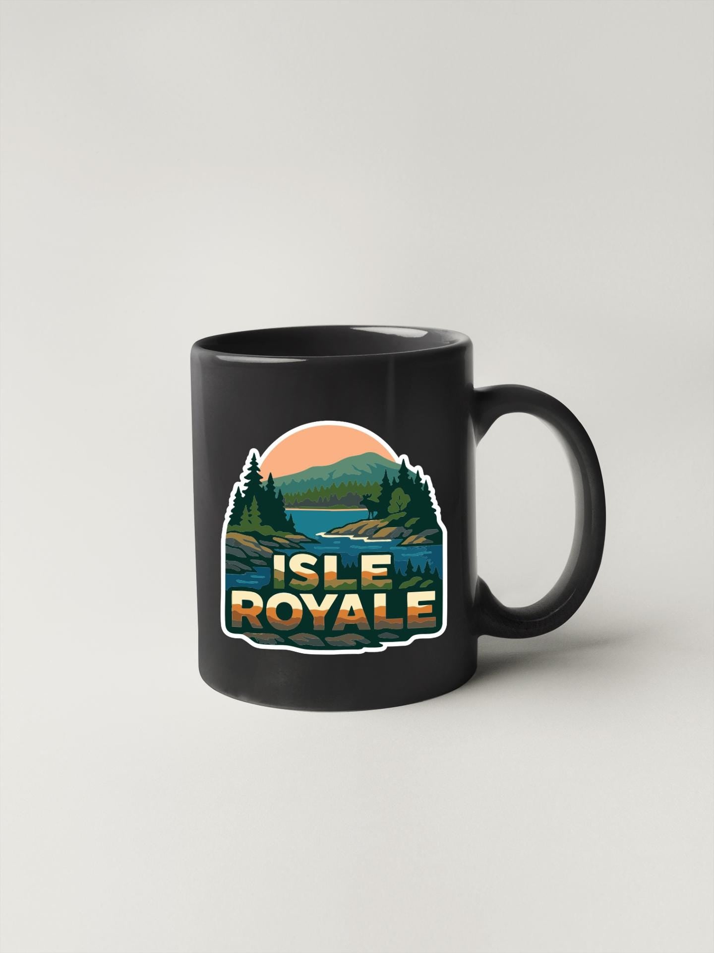 A black coffee mug with a graphic design depicting a scenic landscape with mountains, trees, and a lake.