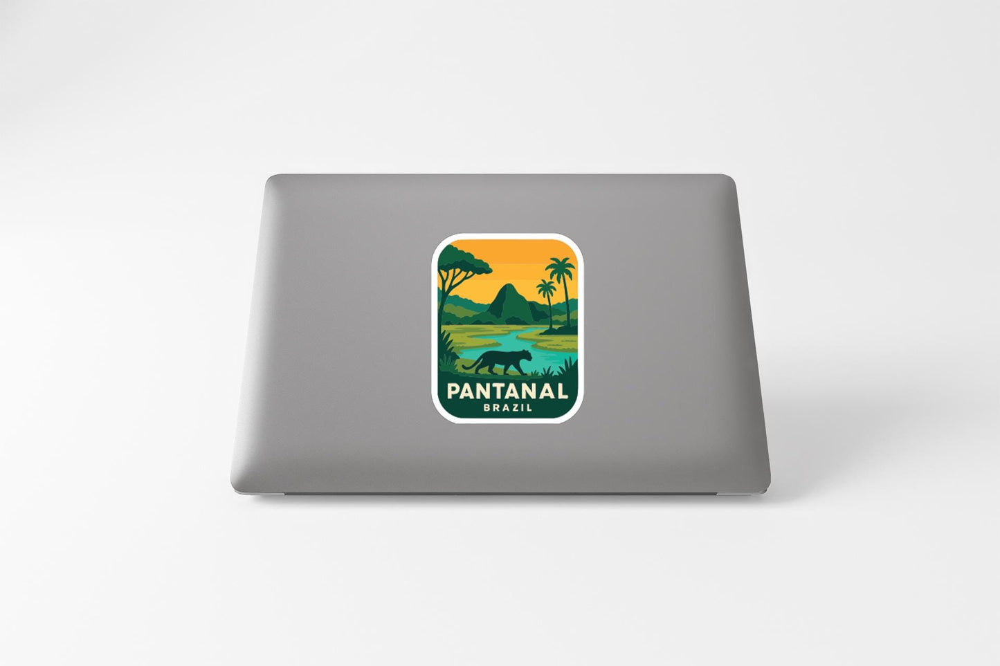 A sticker on the back of a laptop displaying a landscape with a pantan, palm trees, and a body of water.