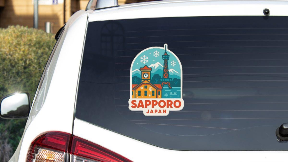 A sticker on the rear window of a white car, depicting a cityscape with a clock tower and mountains in the background, along with the text "SAPPORO JAPAN".
