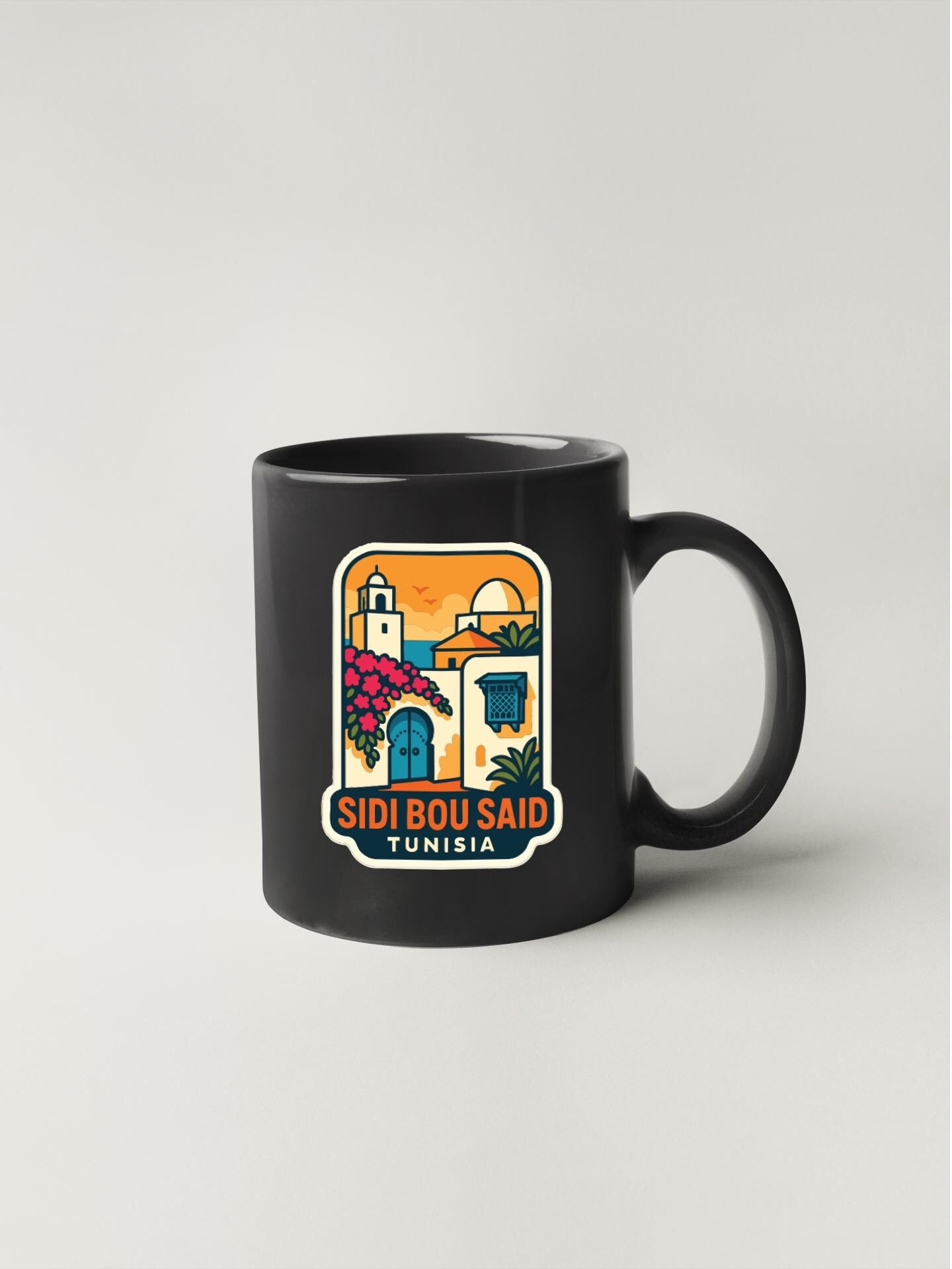 A black coffee mug with a colorful illustration of a building and text that says "SIDI BOU SAID TUNISIA".