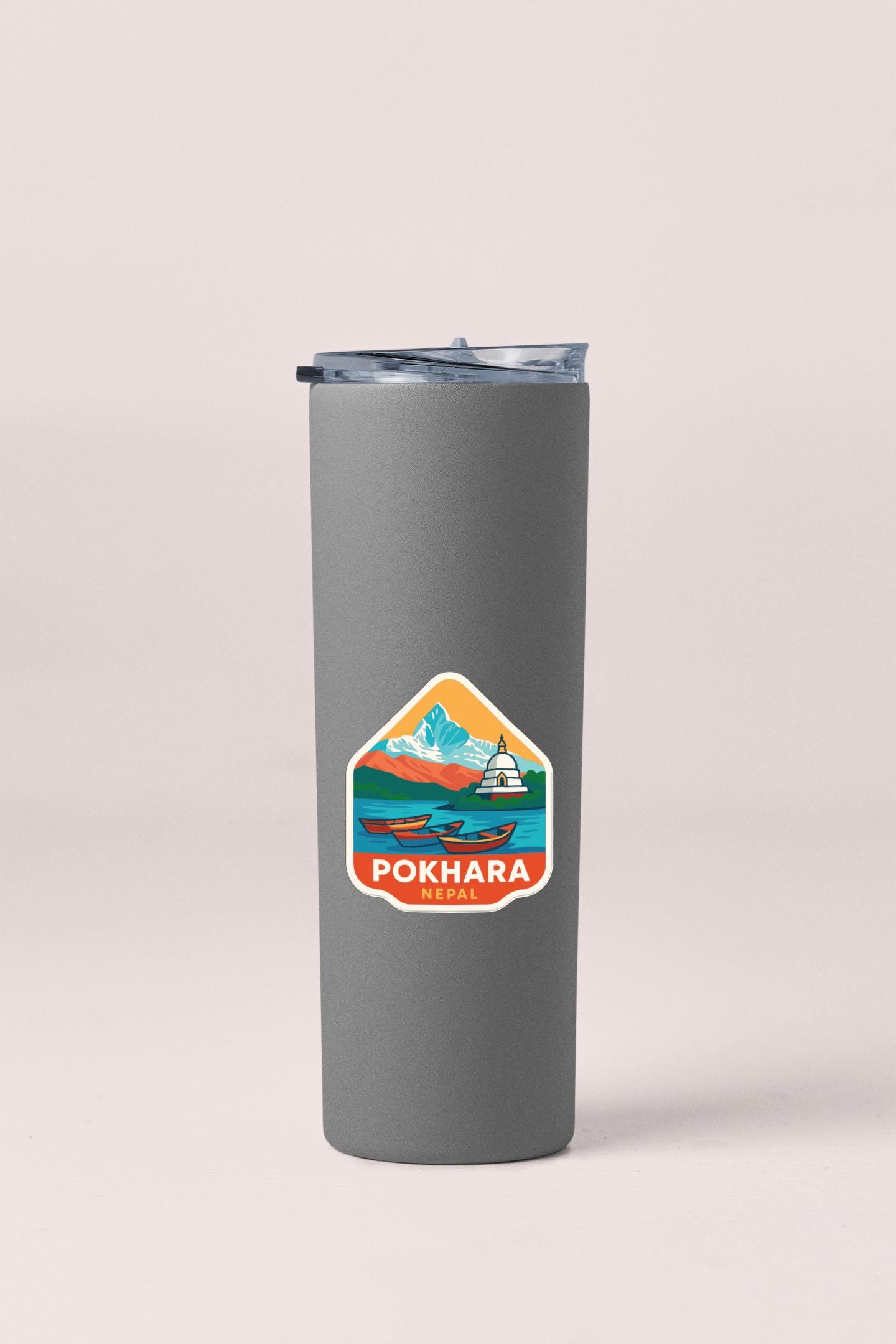 A gray insulated tumbler with a sticker depicting a mountain landscape and a temple.