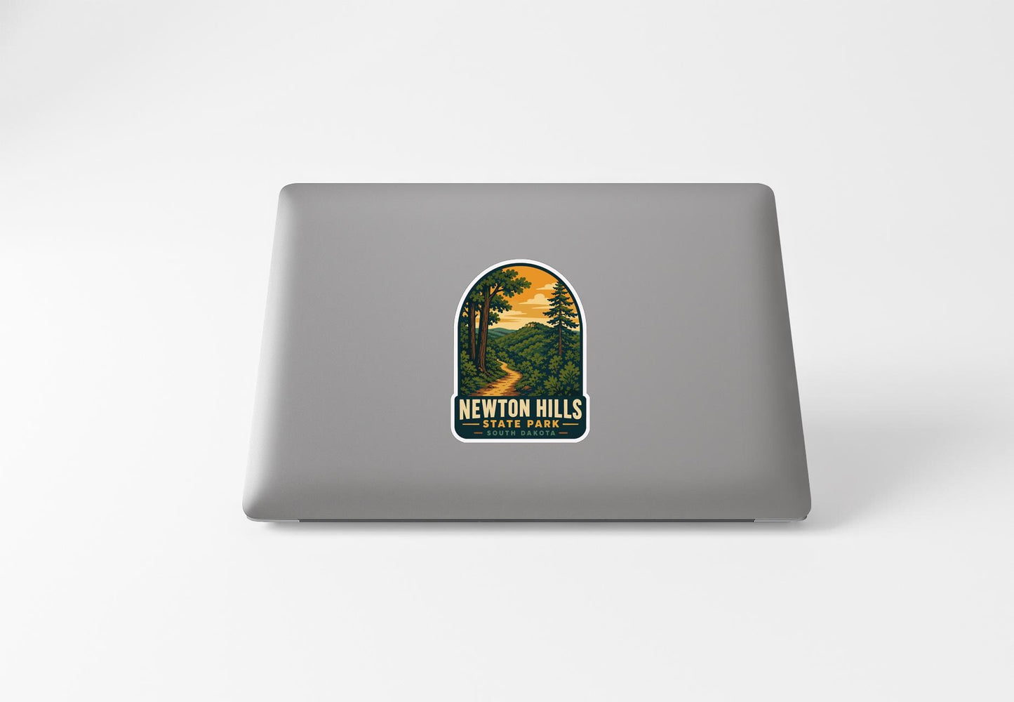 A sticker on the back of a laptop, depicting a scenic landscape with a winding path and trees.