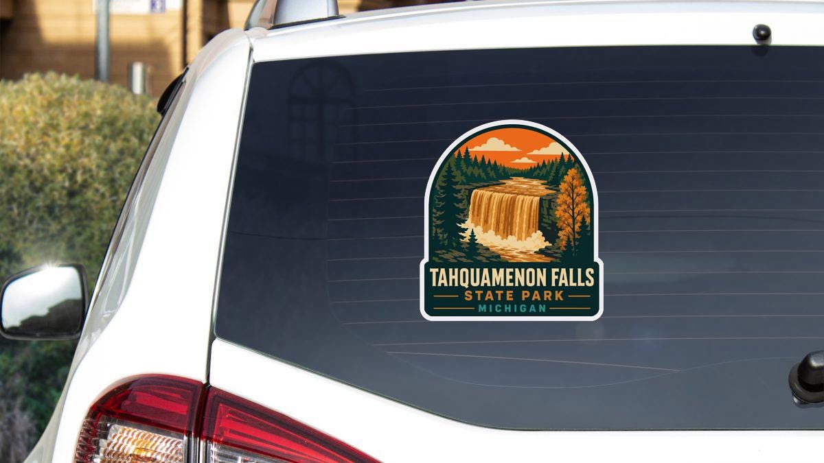 A sticker on the rear window of a white car, depicting a scenic waterfall surrounded by trees and mountains.