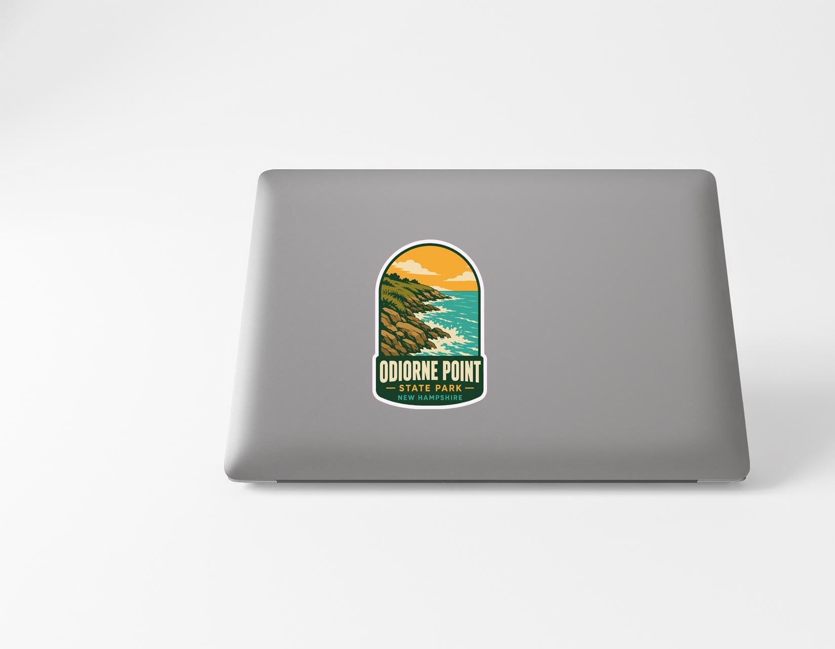 A sticker on the back of a laptop, depicting a scenic landscape with mountains, water, and a sunset.