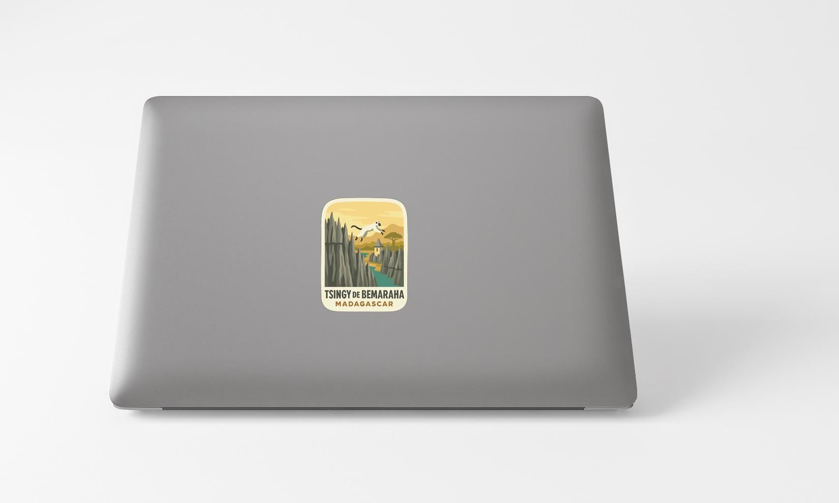 A sticker on the back of a laptop, depicting a scenic landscape with mountains and a body of water.