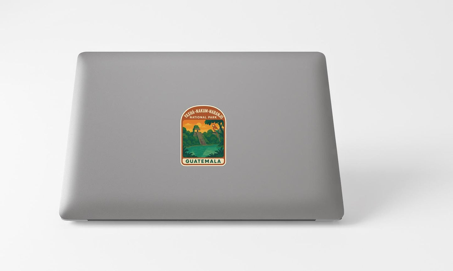 A sticker on the back of a laptop, depicting a scenic landscape with mountains and a lake.
