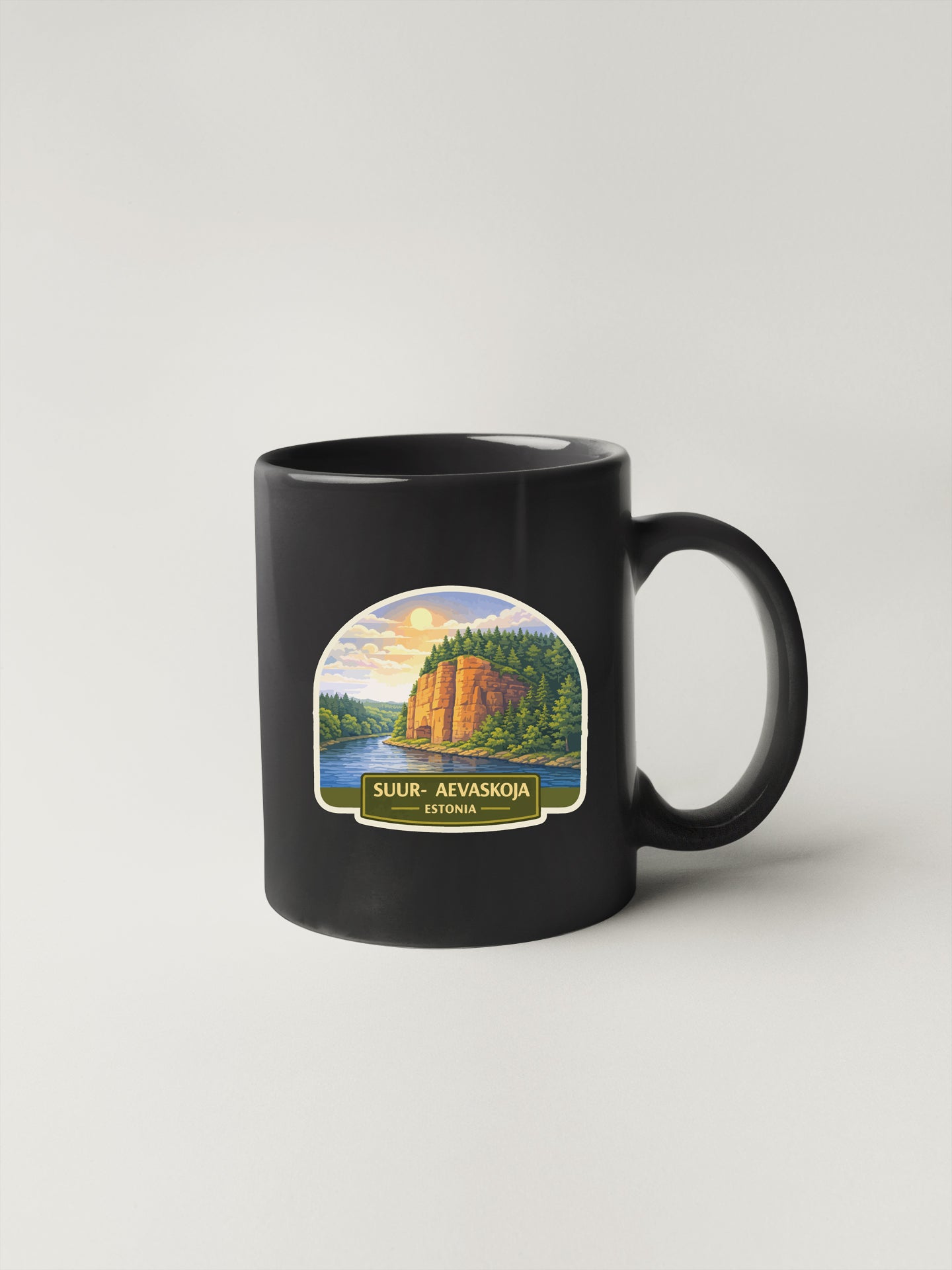 A black coffee mug with a label depicting a scenic landscape, including a mountain, river, and forest.