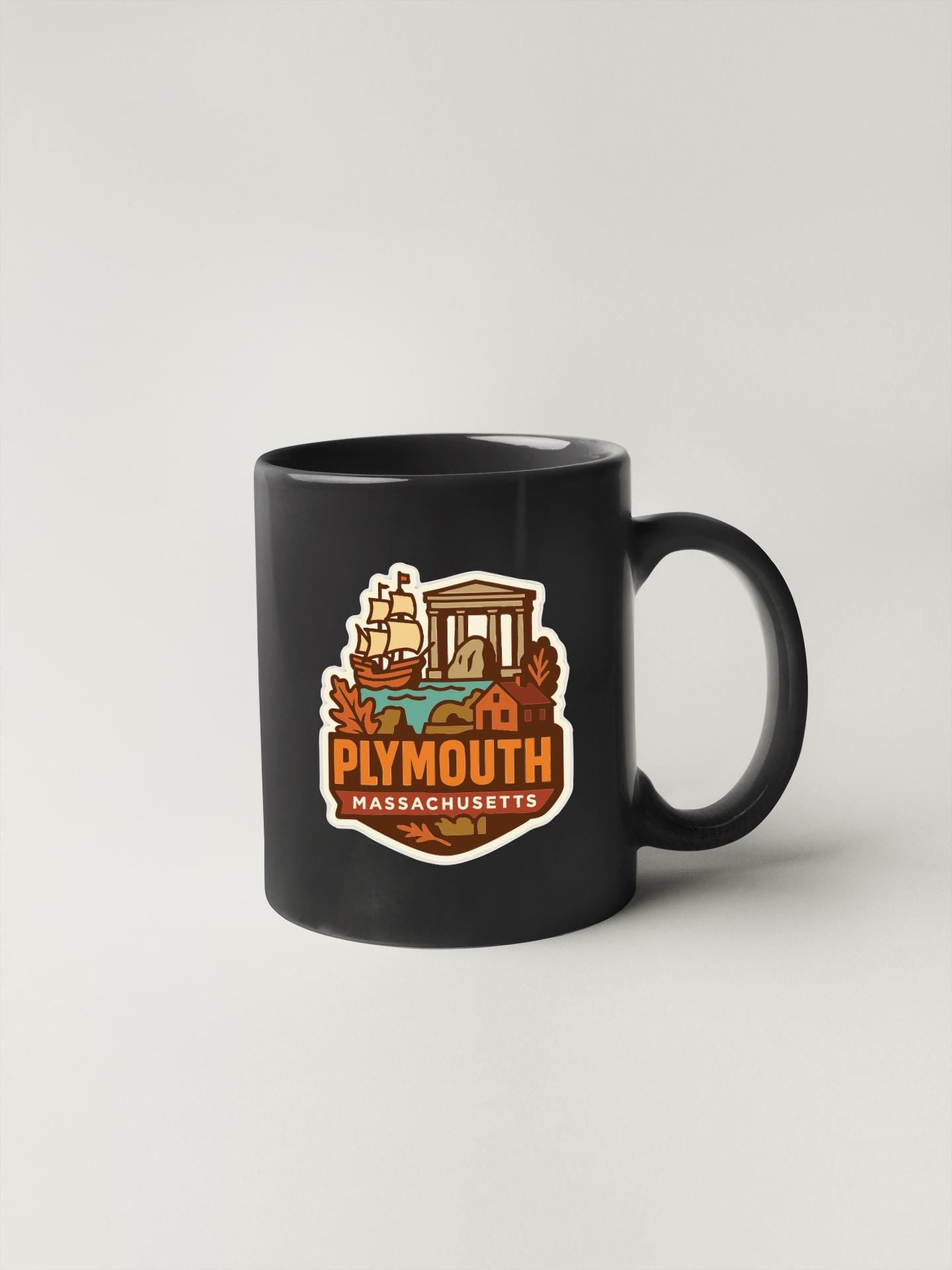 A black coffee mug with a graphic design featuring a ship, a building, and the text "Plymouth, Massachusetts" printed on it.